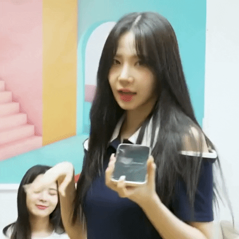 A woman dances for the camera while holding her phone in front of her face